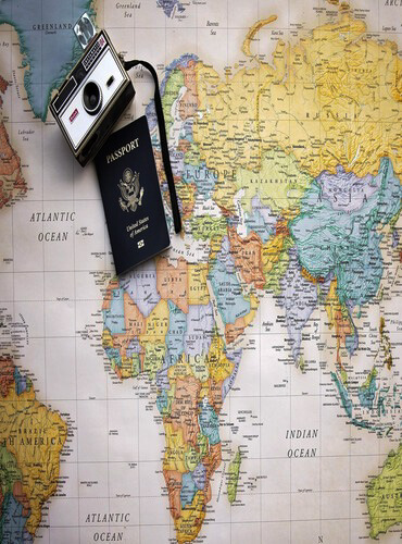 Flat lay of travel planning essentials including a world map, passport, and vintage camera for planning itineraries