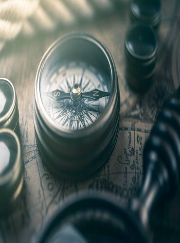 Antique compass resting on a vintage map representing global destination guides for Switzerland and India.