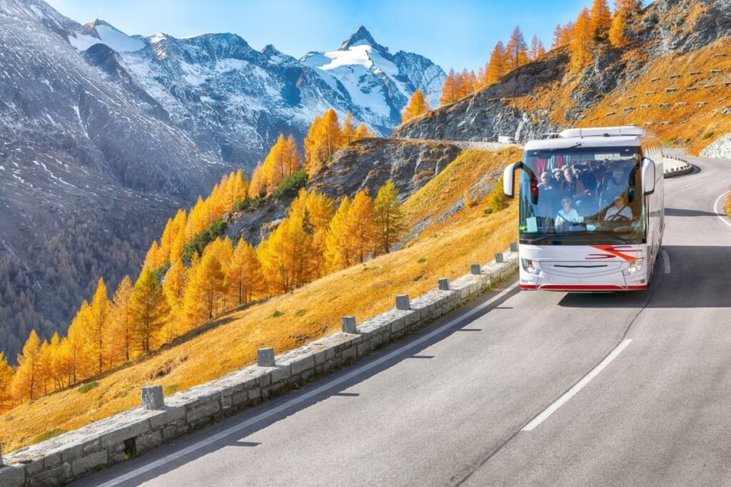 Bright  Swiss PostBus navigating a winding mountain road in the Alps.